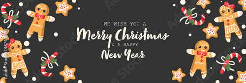 Christmas ginger bread in boy, girl and star shape and candy canes decorated with holly berry branch on black background with Merry Christmas and a Happy New Year text design for banner, frame