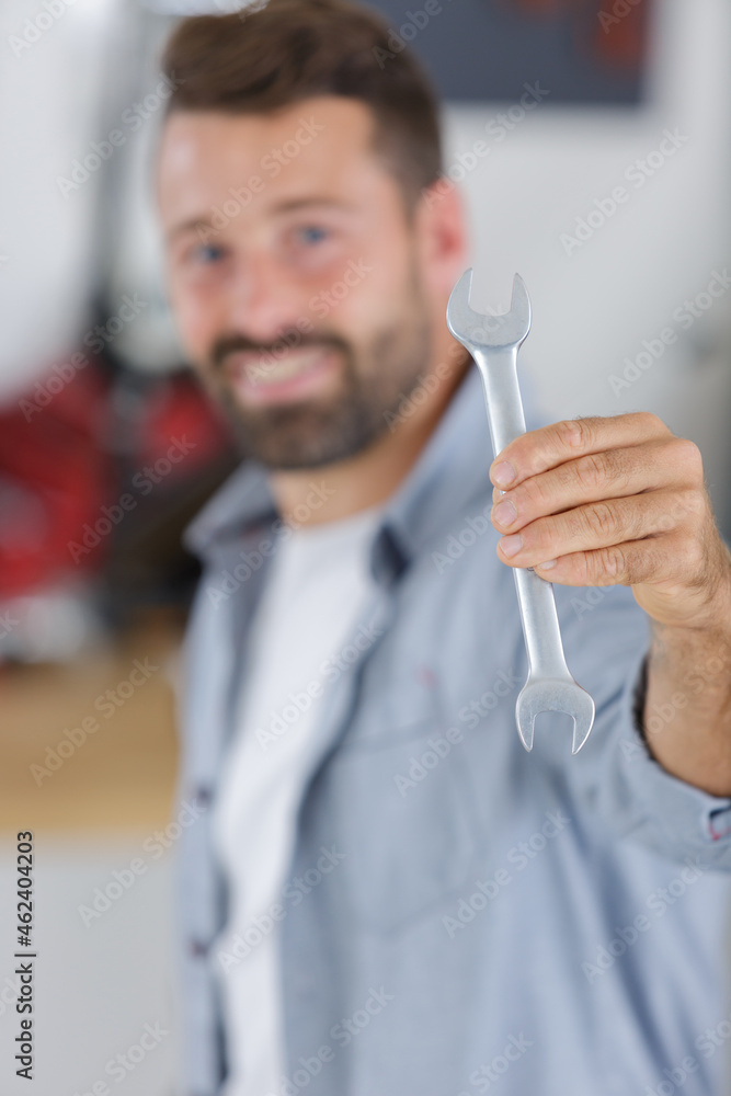 portrait of smiling male mechanic showing spanner portrait of smiling male mechanic showing spanner