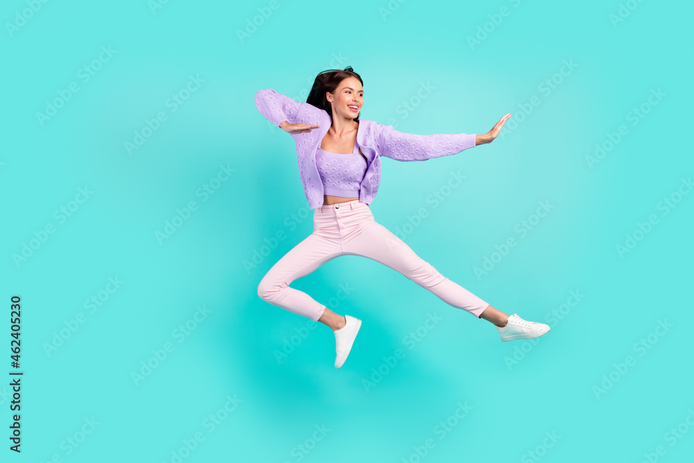 Photo of sweet strong young lady wear violet outfit smiling jumping high practicing karate isolated turquoise color background