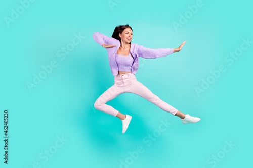Fototapeta Naklejka Na Ścianę i Meble -  Photo of sweet strong young lady wear violet outfit smiling jumping high practicing karate isolated turquoise color background