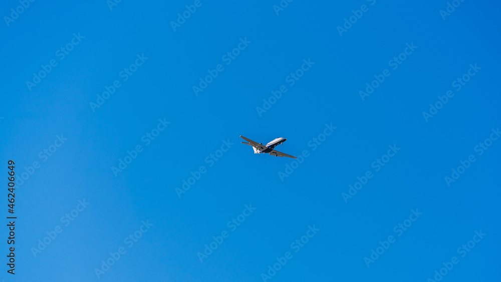 White jet plane in blue cloudless sky on a sunny day