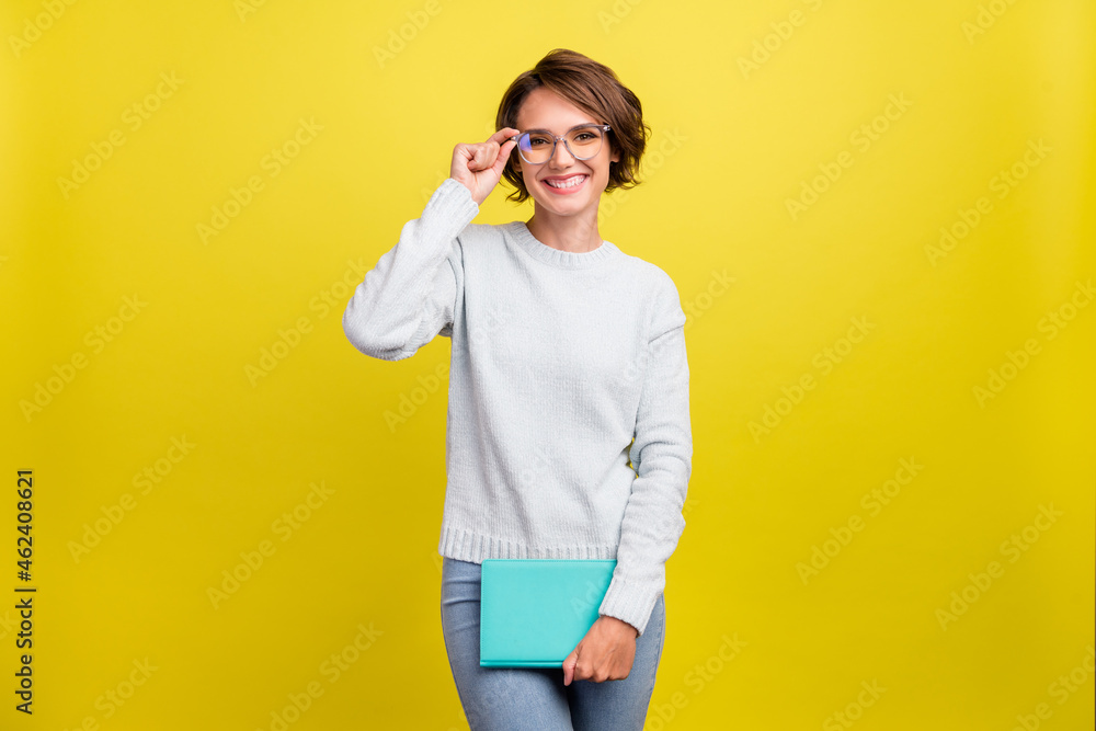 Photo of cute millennial brunette lady with book wear eyeweear blue pullover isolated on yellow color background Photo of cute millennial brunette lady with book wear eyeweear blue pullover isolated on yellow color background