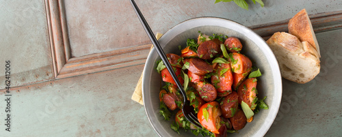 salad bowl with tomatoes, chorizo and basil on the table