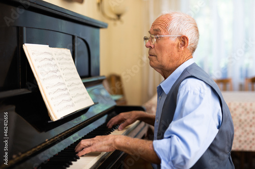 Man practicing playing piano in the living room of his home after retirement from work