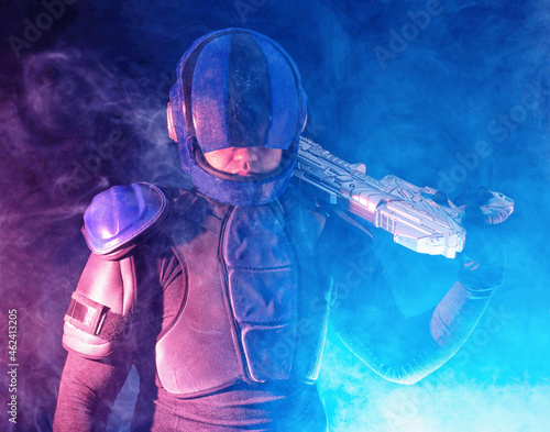 Cyberpunk future concept. Police officer reloads futuristic shotgun in dark. Robot aims at camera. Halfman bionic cyborg releases disconnector assembly of gun. Science fiction scene, fantasy, sci photo