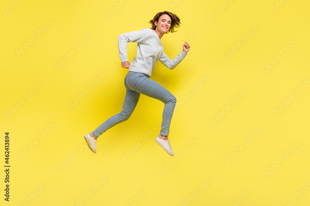 Full length profile photo of funny millennial brunette lady run wear pullover jeans sneakers isolated on yellow background