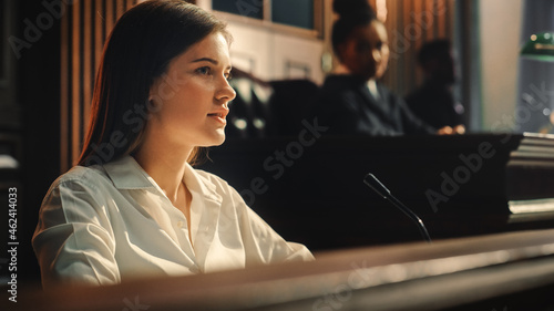 Court of Law and Justice Trial: Portrait of Beautiful Female Witness Giving Evidence to Prosecutor and Defence Counsel, Judge and Jury Listening. Dramatic Speech of Empowered Victim against Crime. photo