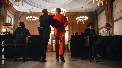 Foto Cinematic Court of Law and Justice Trial Proceedings: Portrait of Accused Male Criminal in Orange Jumpsuit Led Away by Security Guard in Front of Jury
