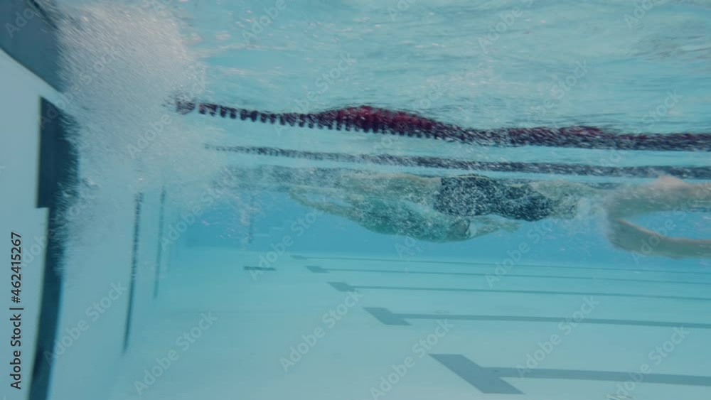 Underwater shot of a swimmers using tumble turn to reverse direction in ...