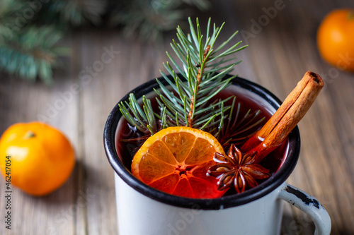 Traditional tasty mulled wine hot drink with mandarin apple spices and christmas tree in white cup photo