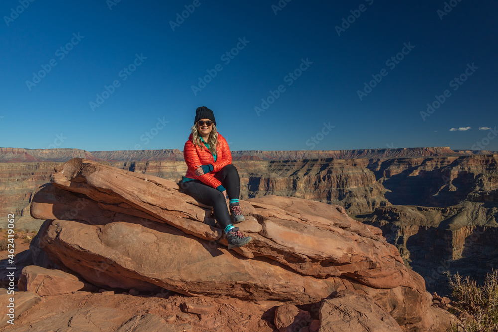 Smiling girl sitting on rock overlooking the Grand Canyon, Arizona, USA