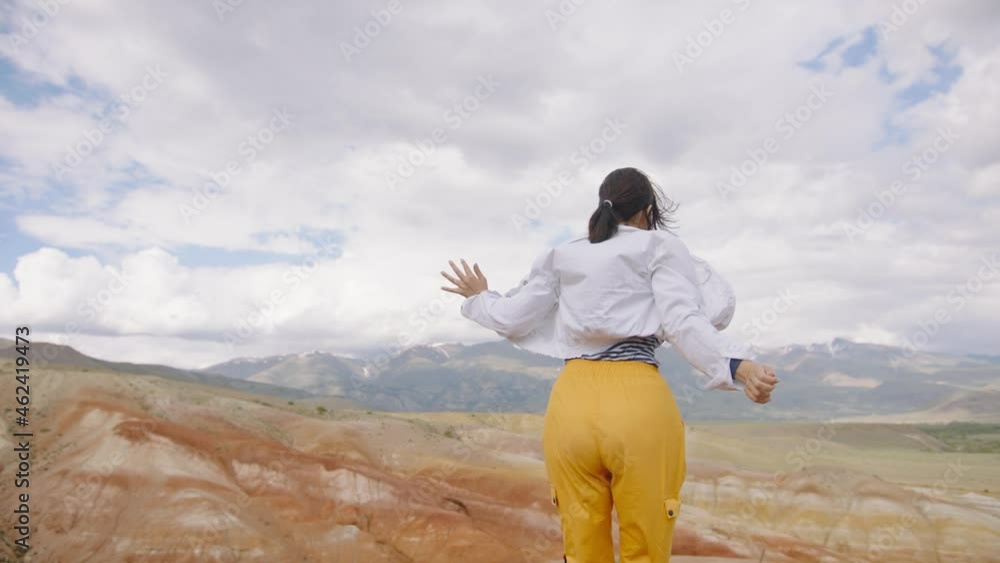 Happy woman traveler laughs and cheerfully whirls in mountains against background of clouds enjoying trip Happy woman traveler laughs and cheerfully whirls in mountains against background of clouds enjoying trip
