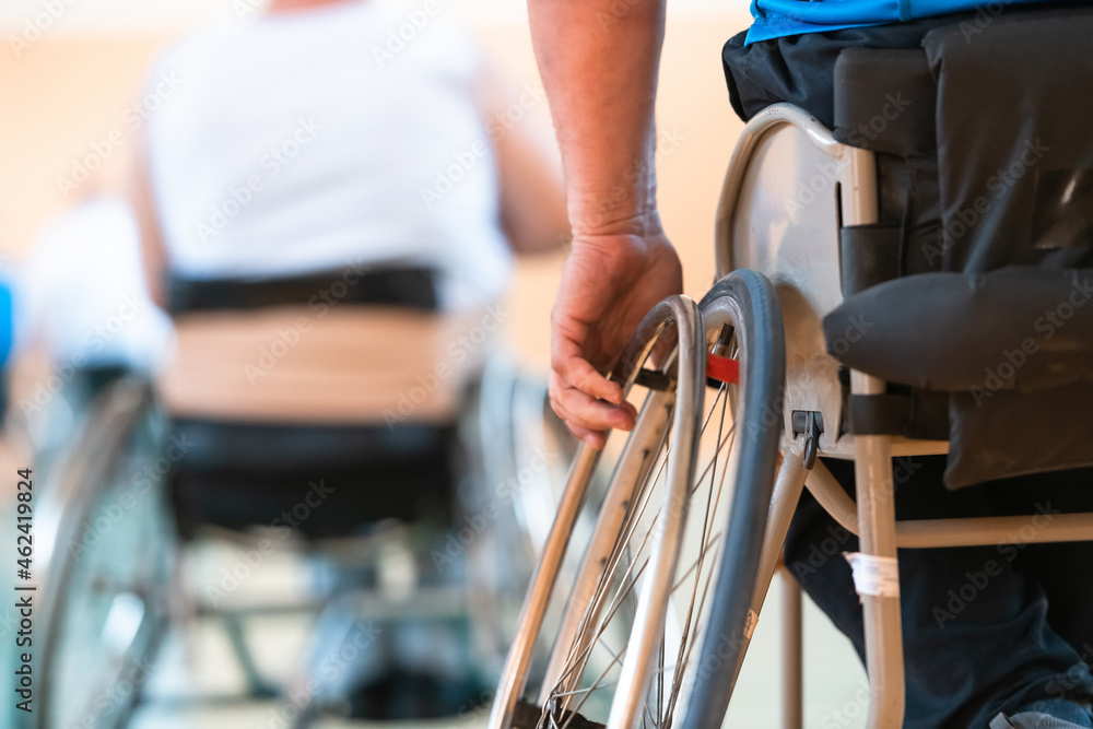Close up photo of wheelchairs and handicapped war veterans playing basketball on the court Close up photo of wheelchairs and handicapped war veterans playing basketball on the court