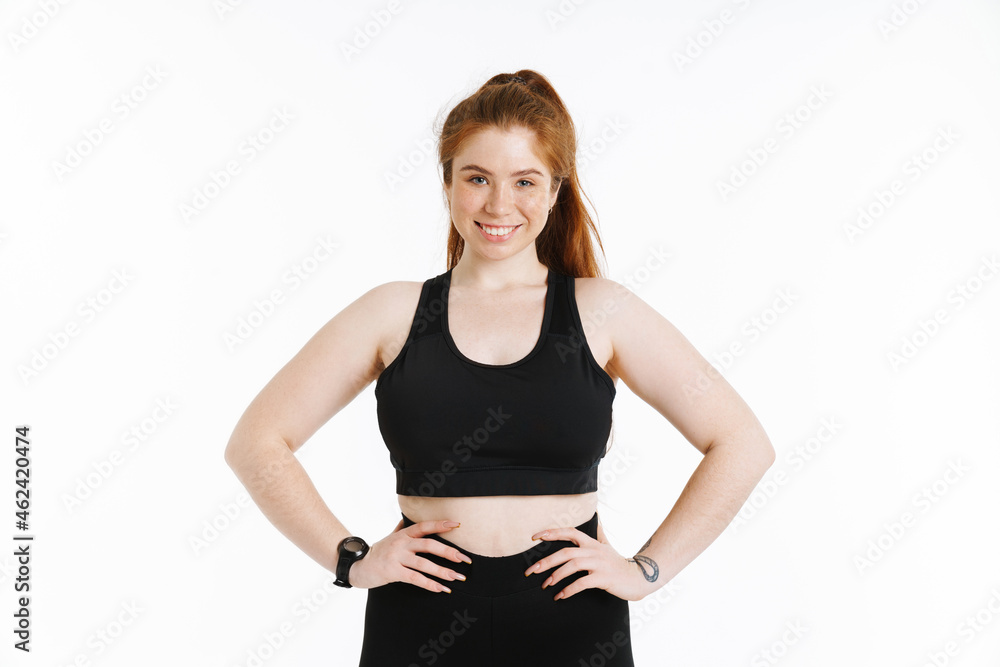 Young ginger woman smiling while holding her hands on waist Young ginger woman smiling while holding her hands on waist