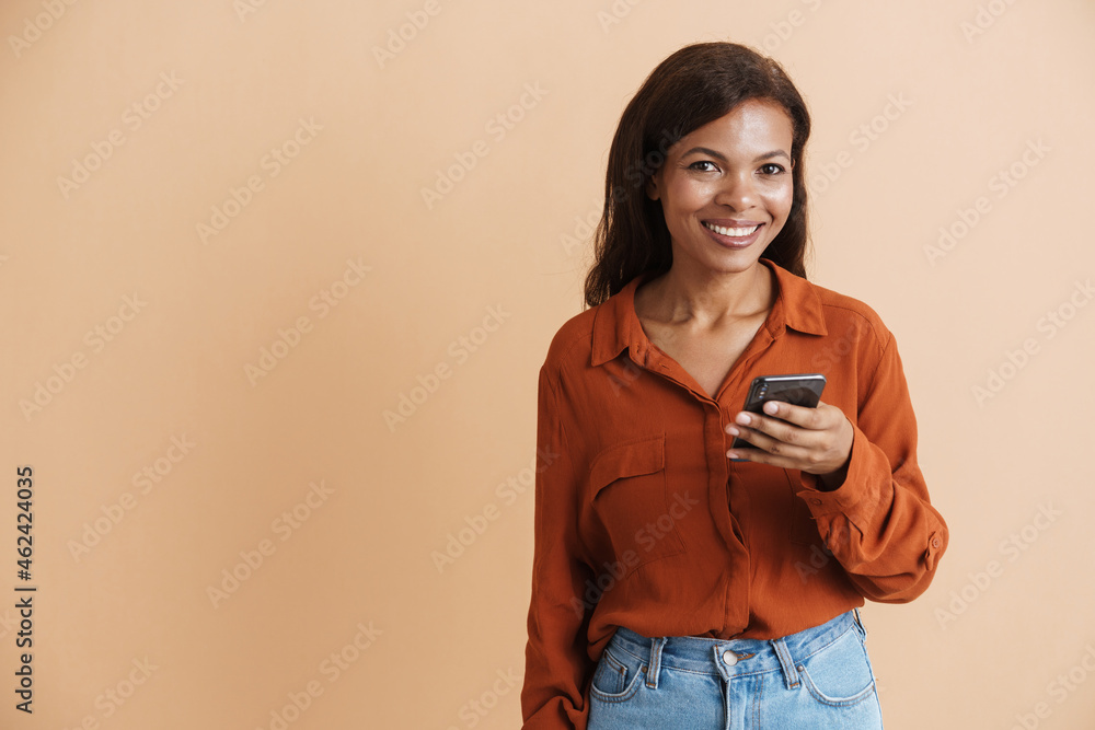 Young black woman wearing shirt smiling and using mobile phone Young black woman wearing shirt smiling and using mobile phone