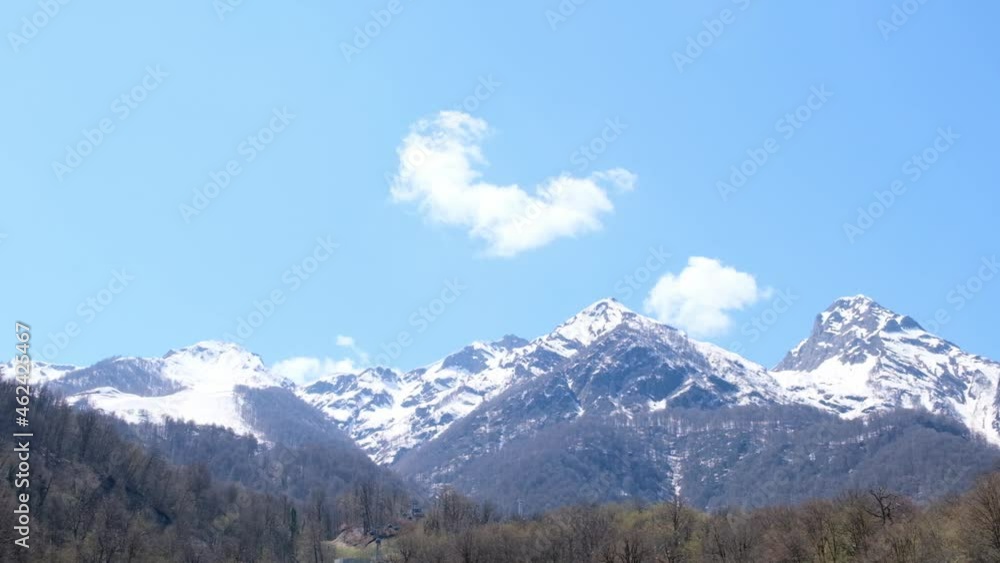 beautiful landscape of snow-capped mountains with white clouds on blue sky on a sunny day at Krasnaya Polyana in Sochi, Russia. Famous ski resort beautiful landscape of snow-capped mountains with white clouds on blue sky on a sunny day at Krasnaya Polyana in Sochi, Russia. Famous ski resort
