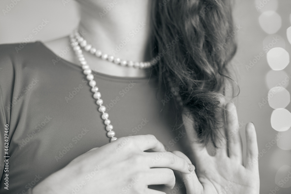  Elegant female jewelry white beads on woman on bokeh background close-up. Christmas and New Year gift concept. Black and white photography