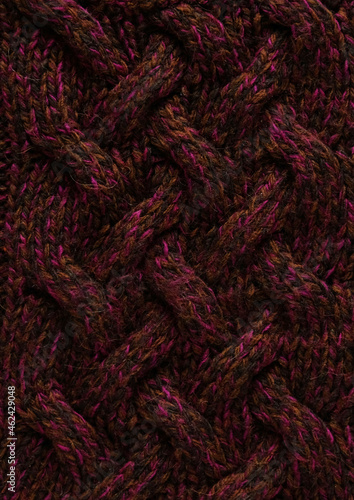 Texture of smooth knitted dark sweater with pattern. Top view, close-up. Handmade knitting wool or cotton fabric texture. Background of knitting patterns with a vertical large Braid Cable.