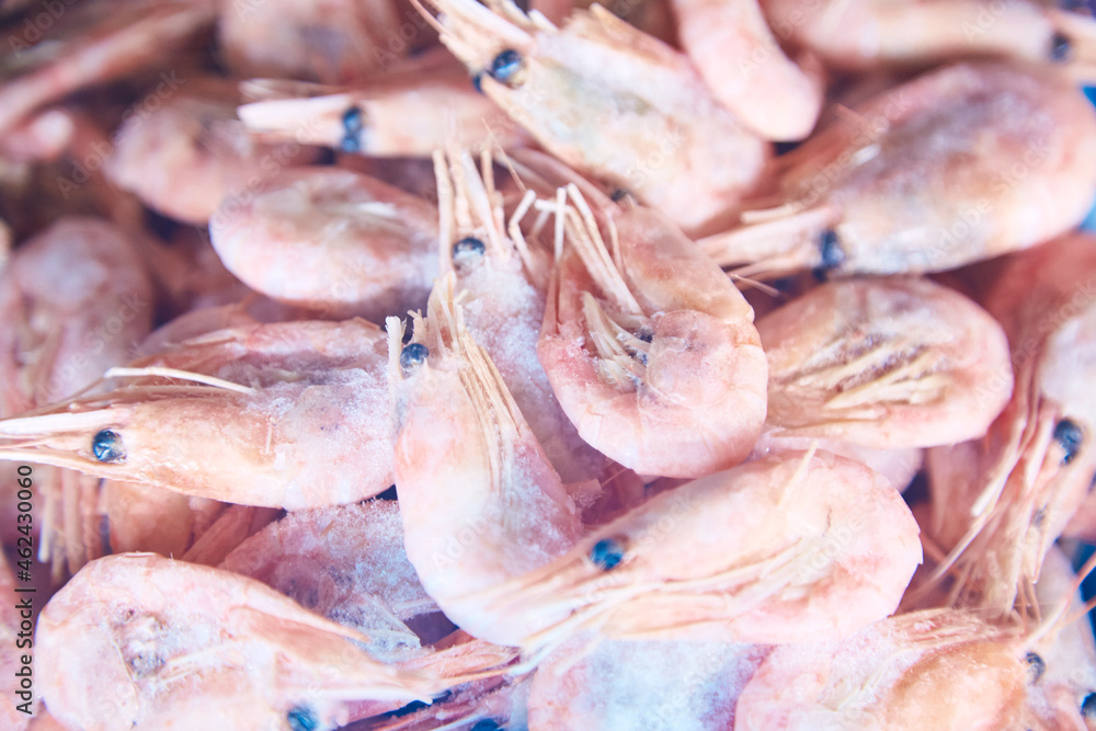 Frozen shrimp in a shop freezer window. Sea and ocean iced fish on a shop display close-up. Fish supermarket. A wide variety of fish