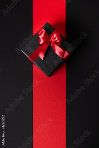 A stylish gift in a dark package and a bright festive ribbon. Minimalism is a vertical image.