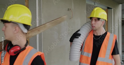 People working in construction site. Clumsy and awkward man creating dangerous situation at work in new house. Two manual workers in funny moment inside building photo