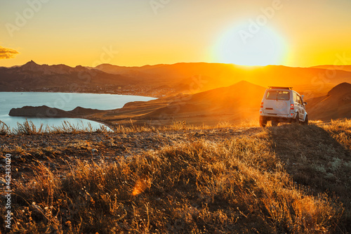 The jeep is standing on the top of the mountain in the sunset. A delightful landscape and the concept of travel, freedom and adventure