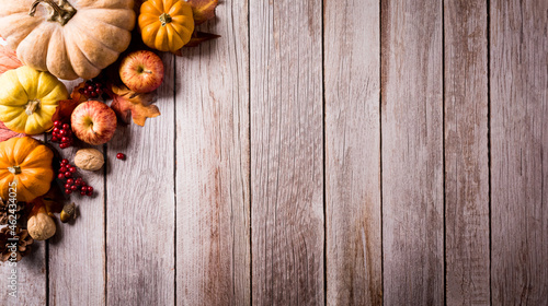 Thanksgiving and autumn composition. Pumpkin, apple,red berry and autumn leaves on dark wooden background. Flat lay, top view with copy space.
