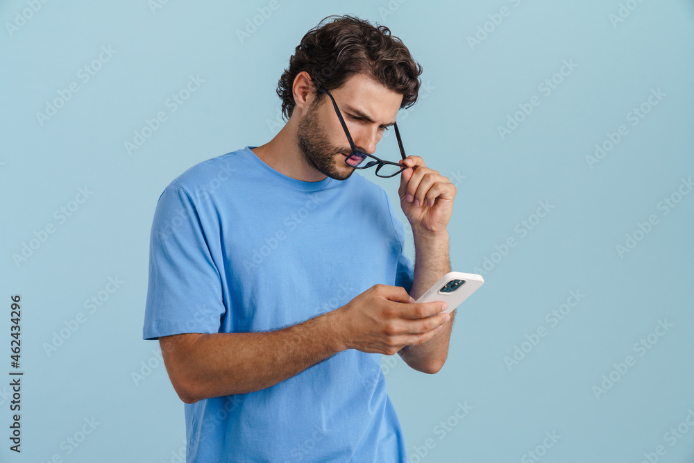 Naklejka premium Young brunette man in eyeglasses using mobile phone