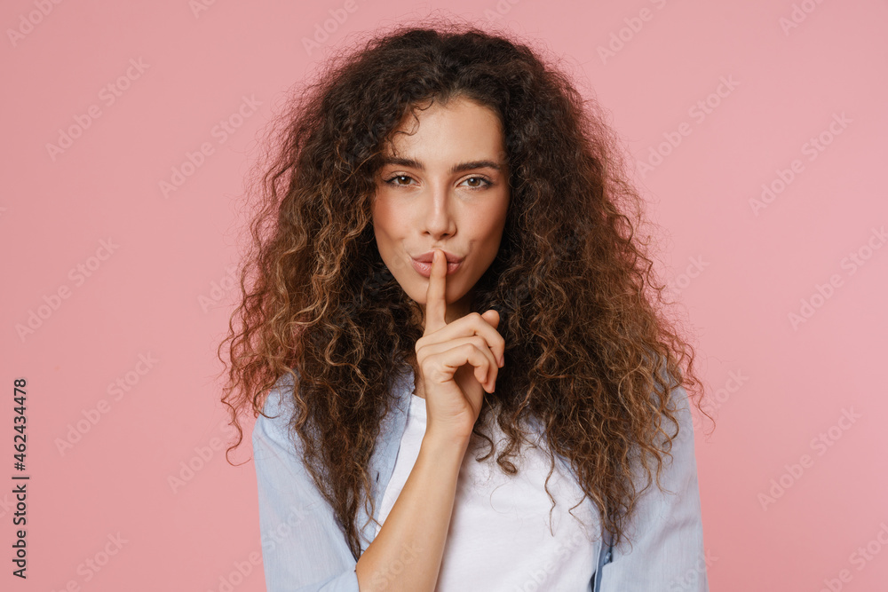 Young brunette woman smiling and showing silence gesture Young brunette woman smiling and showing silence gesture