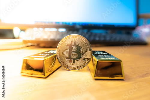 Bitcoin laying on stacked gold bars (gold ingots) rendered with shallow depth of field. Bitcoin as desirable as gold concept photo