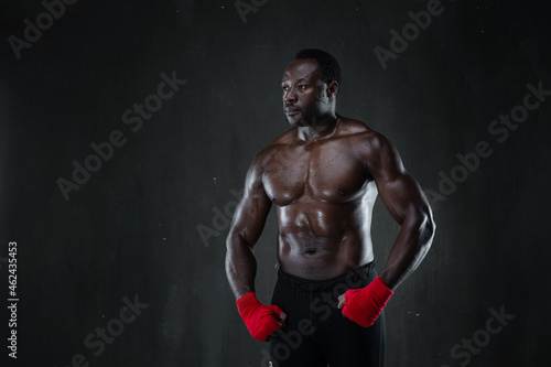 African american muscular athlete over black background. Afro sporty man in boxing style. Strength, sport and motion project.