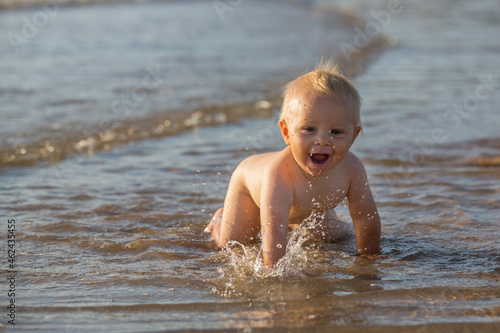 Fototapeta Naklejka Na Ścianę i Meble -  Baby boy, playing on the beach in the water, smiling