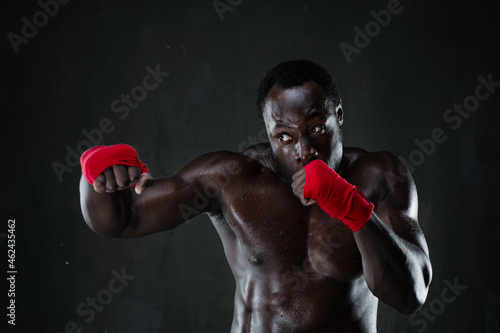 Athletic afro boxer during boxing training. Fitness african american muscular model over black background. Strength, fighting and motion project. © Admiral