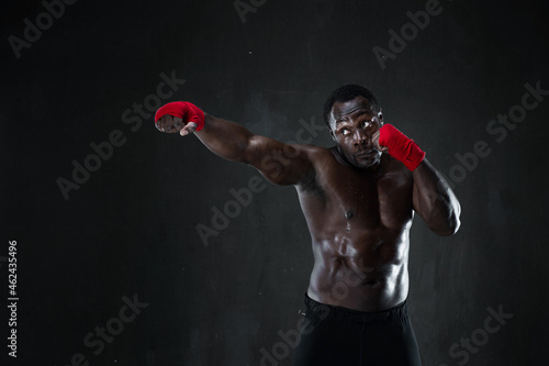 Sporty man during boxing training. Fitness african american muscular model over black background. Strength, fighting and motion project. © Admiral
