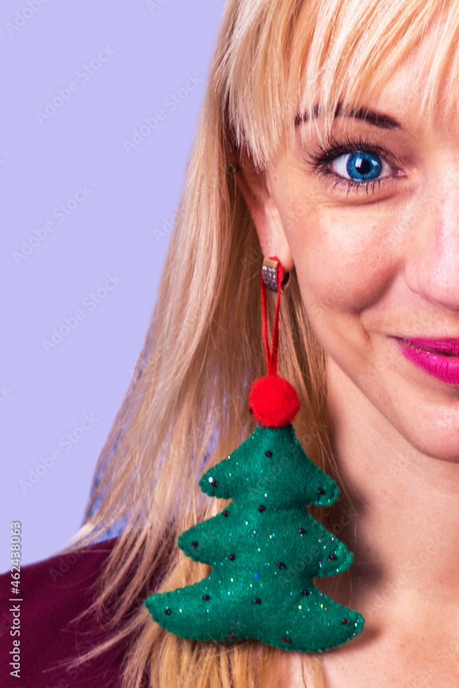 Beautiful girl with earring in the shape of a Christmas tree in her ear