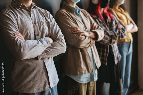 Multiracial man and women in face mask standing by wall