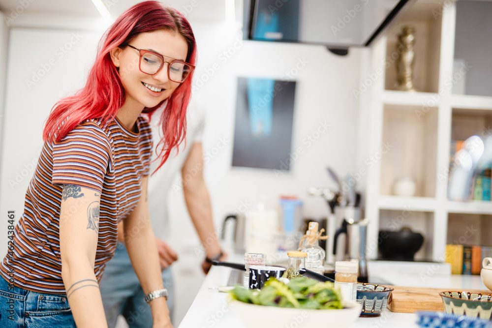 Young white couple smiling while cooking together in kitchen Young white couple smiling while cooking together in kitchen