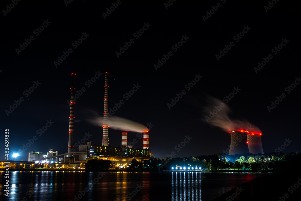 Obraz na płótnie Night picture of distant black coal-fired power plant. Blurry view for the smoke coming out of the chimneys. Photo taken in evening under natural lighting conditions. w salonie