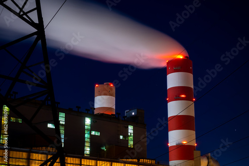 Night picture of the coal-fired power plant. Blurry view for the smoke coming out of the chimneys. Photo taken in evening under natural lighting conditions.