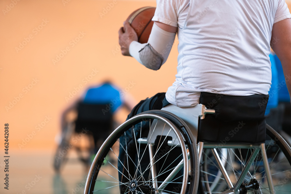 Obraz premium Close up photo of wheelchairs and handicapped war veterans playing basketball on the court