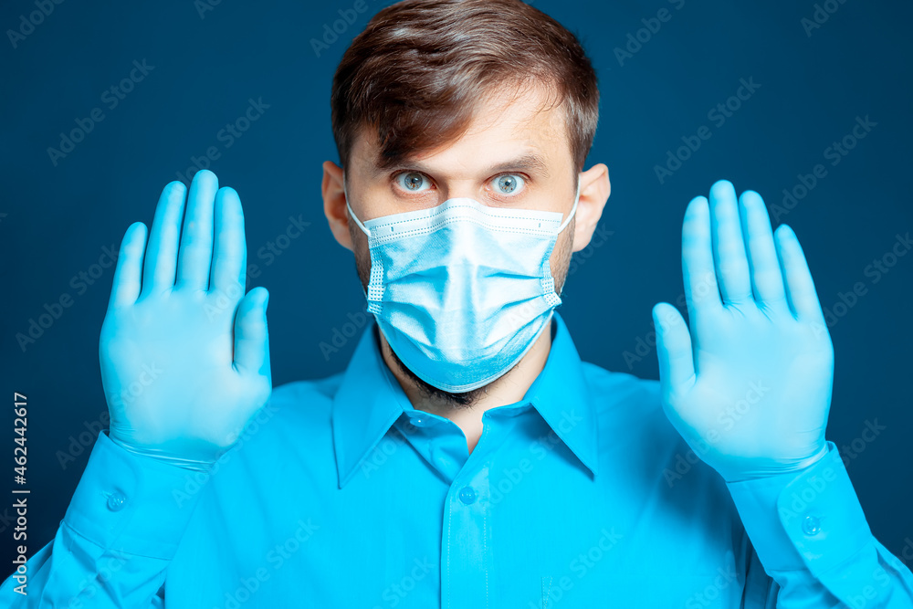 doctor in a medical mask and gloves, in a blue uniform gestures with his hands. doctor in a medical mask and gloves, in a blue uniform gestures with his hands.