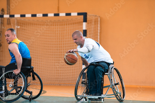 Close up photo of wheelchairs and handicapped war veterans playing basketball on the court