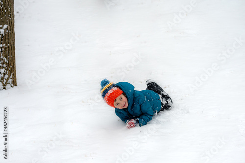 Little boy laughing and rolling in a field of snow