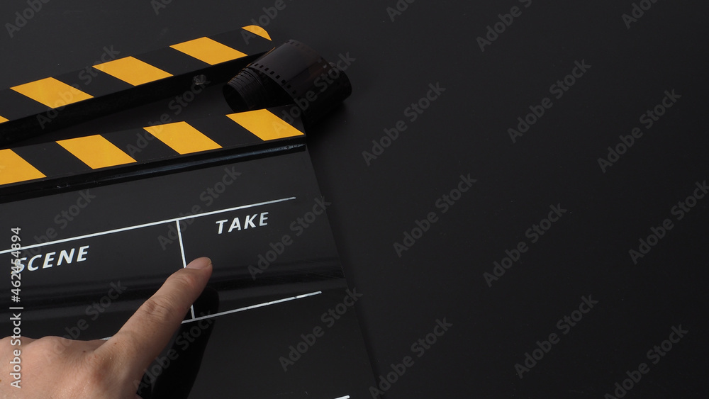 Yellow and black Clapper board or movie slate on black background and hand pointing. It use in movie and video production industry.