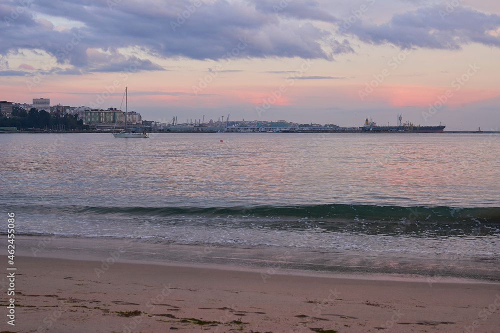 sunrise on the beach of santa cristina, with the port and part of the city of la coruña in the background