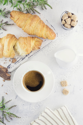 Cup of coffee with croissants, a slice of natural chocolate, milk and cane organic unrefined sugar on a vintage table. Provence style. Healthy vegetarian food. Flat lay