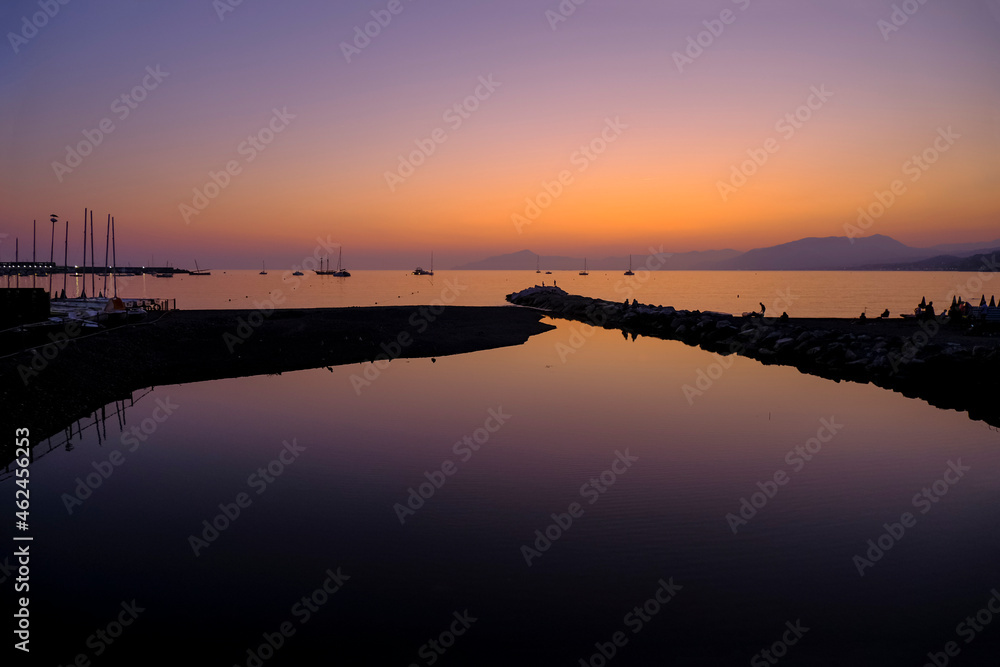 Beautiful pink sunset in sea across boats, mountains on the horizon. Natural background. vacation at sea