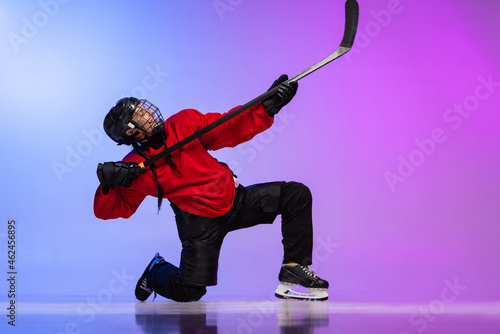 Canvas Print Portrait of professional female hockey player in special protective helmet isolated over gradient blue purple background