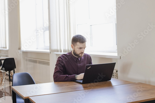 A man sits at a table in the office and works on a computer