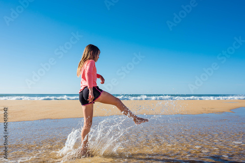 cute little girl having fun barefoot by the ocean